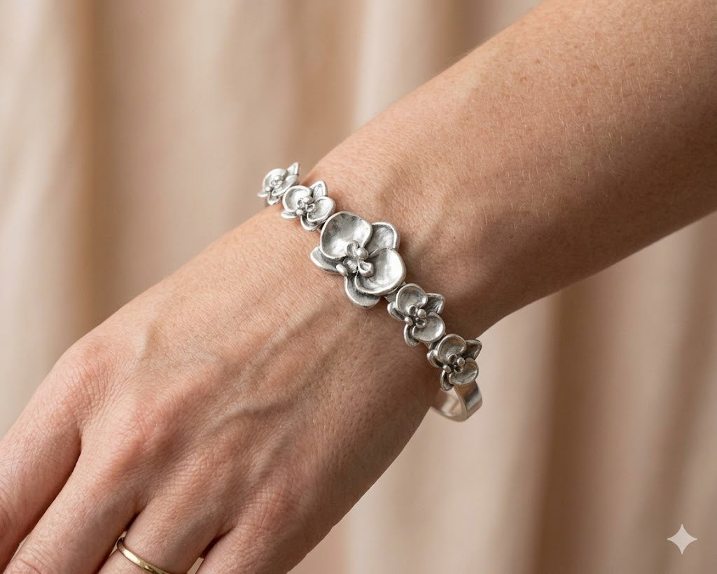 Silver orchid bracelet on a wrist with a beige background